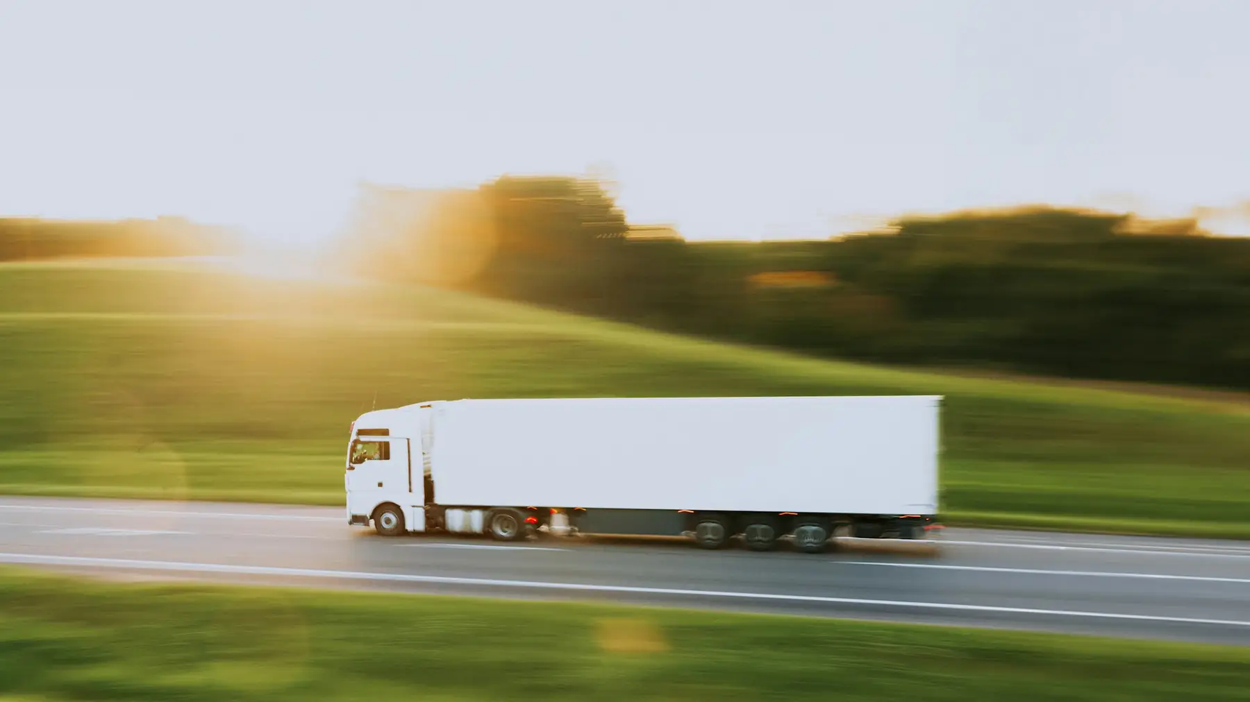 Freight truck moving along a green hillside road
